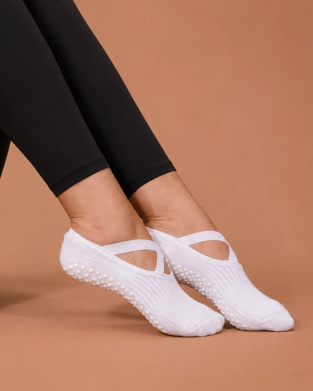 Strappy low-cut grip socks with a criss-cross strap, worn in the studio